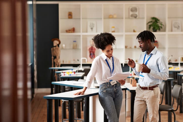 Two teachers discussing school material in a classroom.